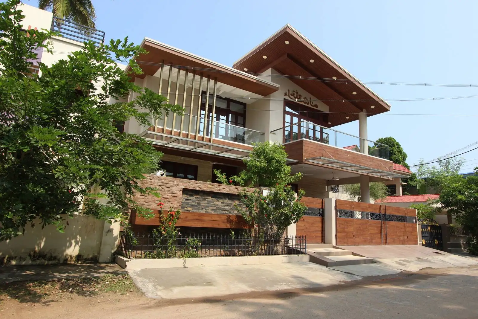 The entrance gate and boundary wall feature horizontal panels and sleek framing, ensuring privacy while echoing the home's overall design.