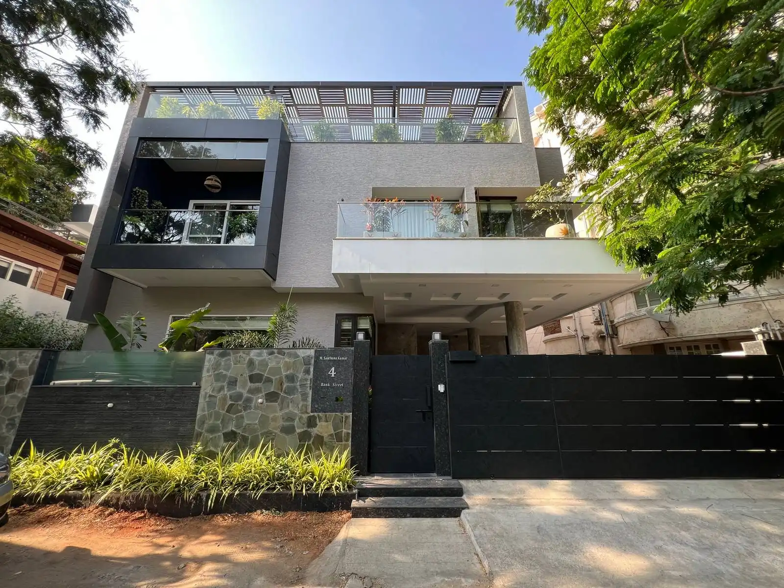 The entrance is marked by a sleek, modern black gate with horizontal slats, providing both security and a contemporary aesthetic.