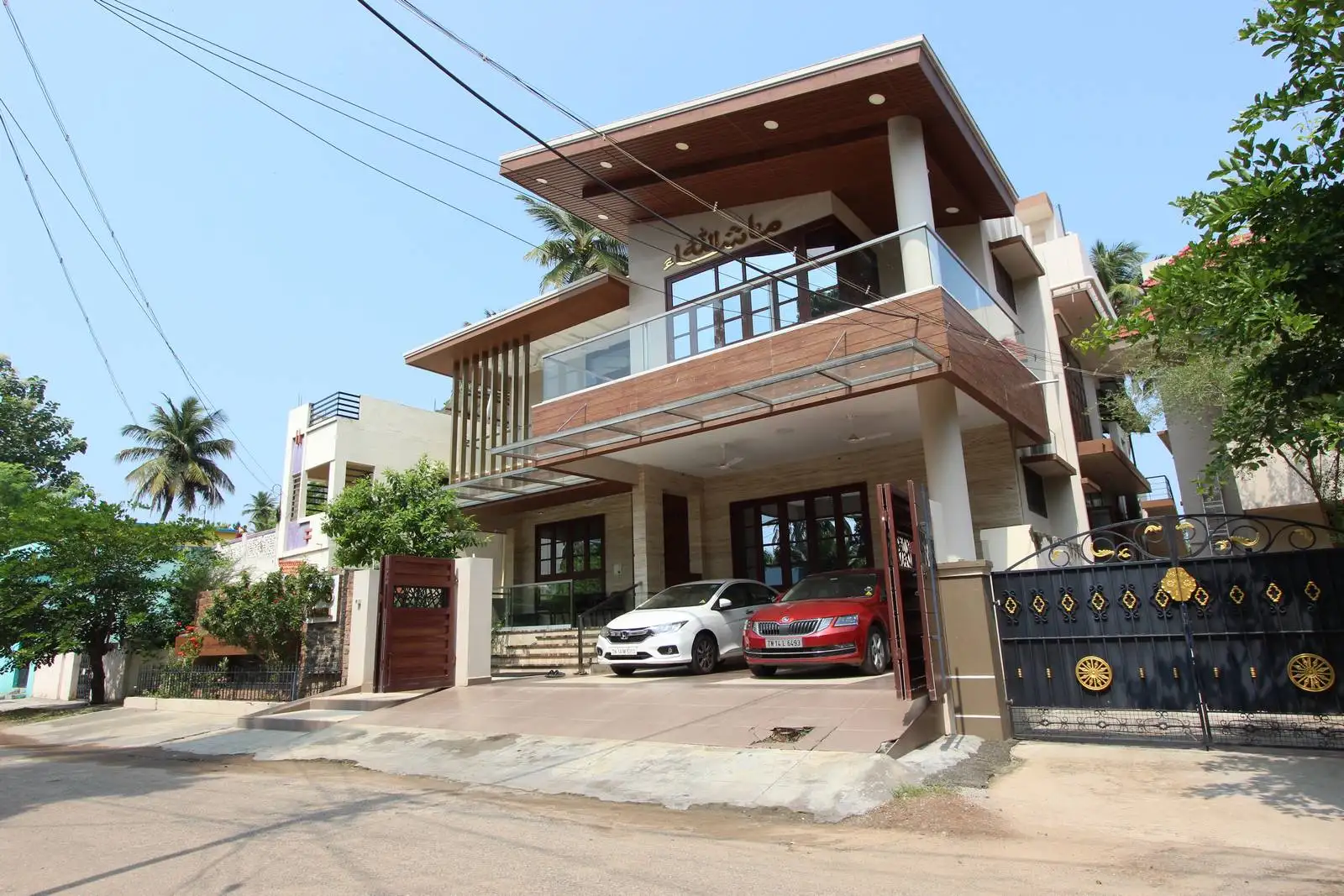 Wood-accented balcony and facade create visual unity, while large windows enhance light and indoor-outdoor flow. A covered parking space with a sloped driveway offers easy access.