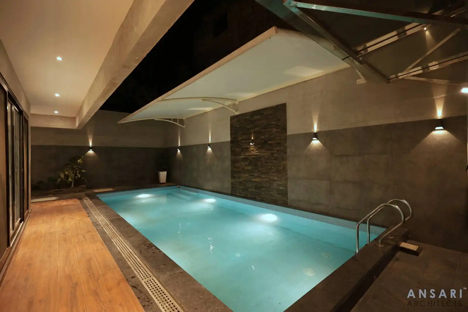 The swimming pool enclosed design with solid walls offers privacy and a peaceful atmosphere, making it an ideal space for both relaxation and fitness within a stylish architectural setting.