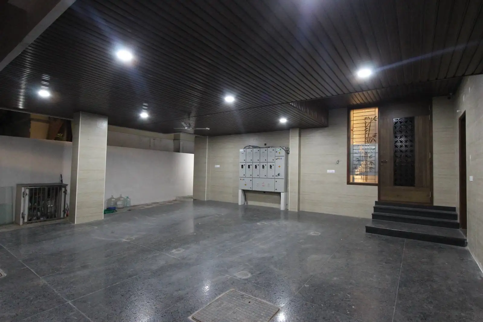 Steps lead to a main entrance framed by a decorative window grill and warm lighting, creating a welcoming transition from parking to interior.