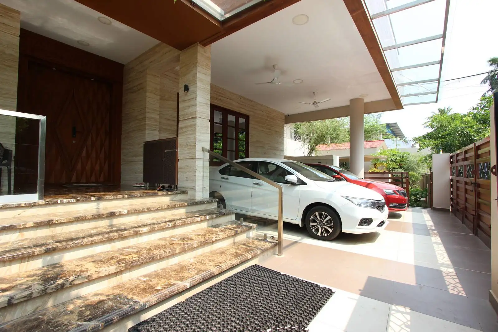 Elevated entrance with elegant marble steps and a bold geometric main door creates a grand welcome. A spacious, partially covered porch with car parking and durable flooring ensures comfort and functionality.