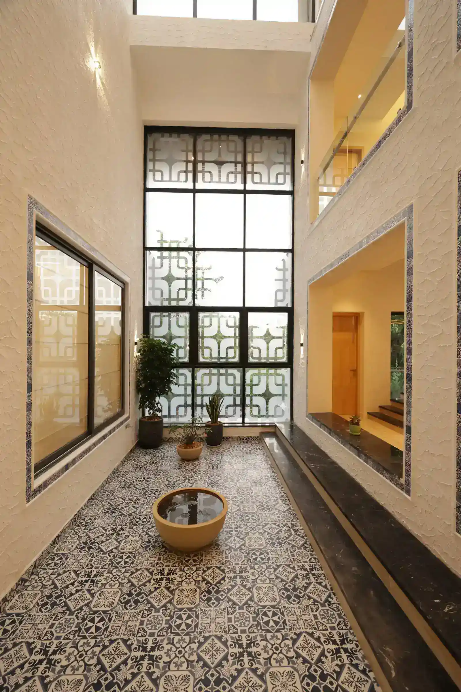 Large windows on all sides visually connect the courtyard to adjacent interior spaces, enhancing openness and transparency.
