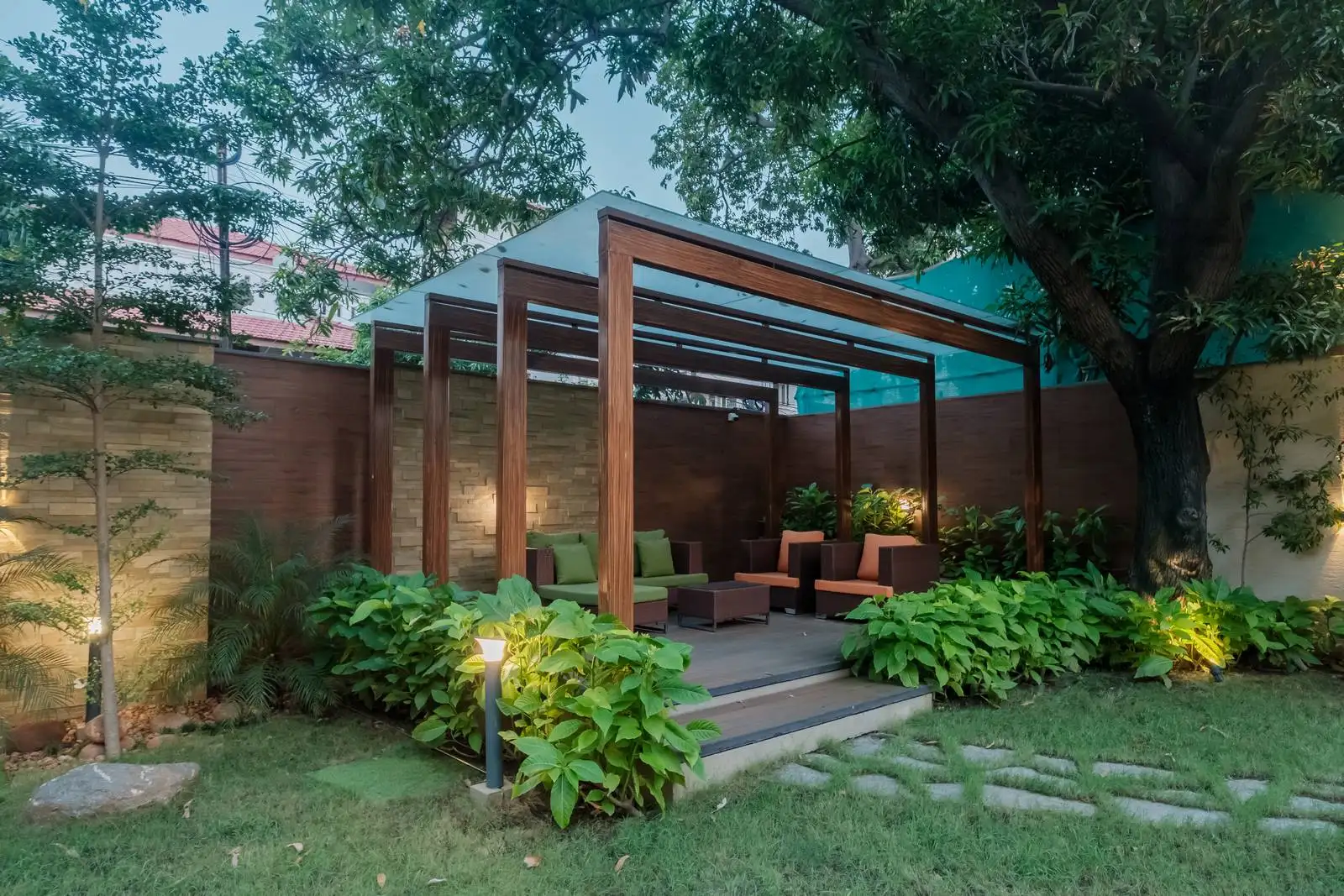 Subtle wall-mounted lighting on the stone wall creates a soft, ambient glow, enhancing the space’s usability in the evening and highlighting textures.
