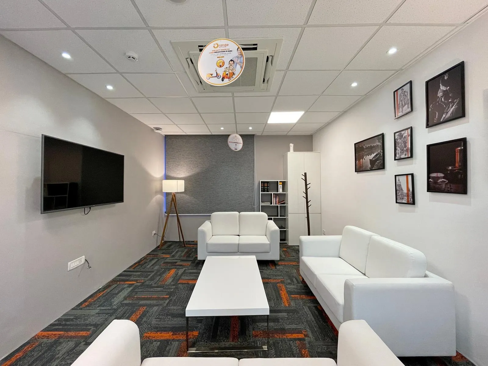The executive lounge features a sophisticated, comfortable layout with white leatherette seating, patterned carpet, and integrated lighting, creating a serene corporate retreat. Neutral finishes, modular furniture, and acoustic ceiling panels enhance functionality, relaxation, and professional elegance.