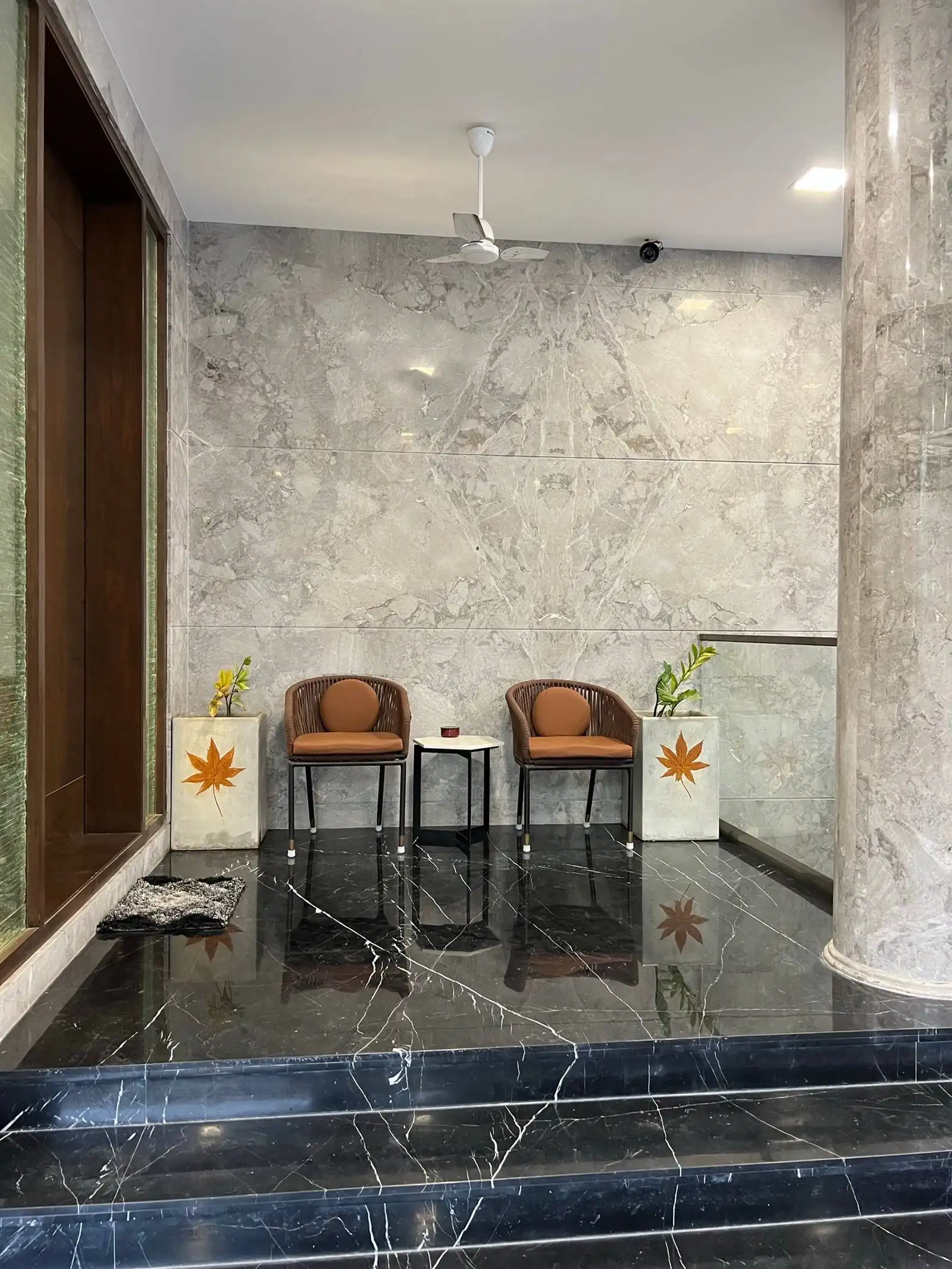 The backdrop is a gray marbled wall, adding a touch of luxury and visual texture to the space.
A ceiling fan is installed above, ensuring air circulation and comfort.