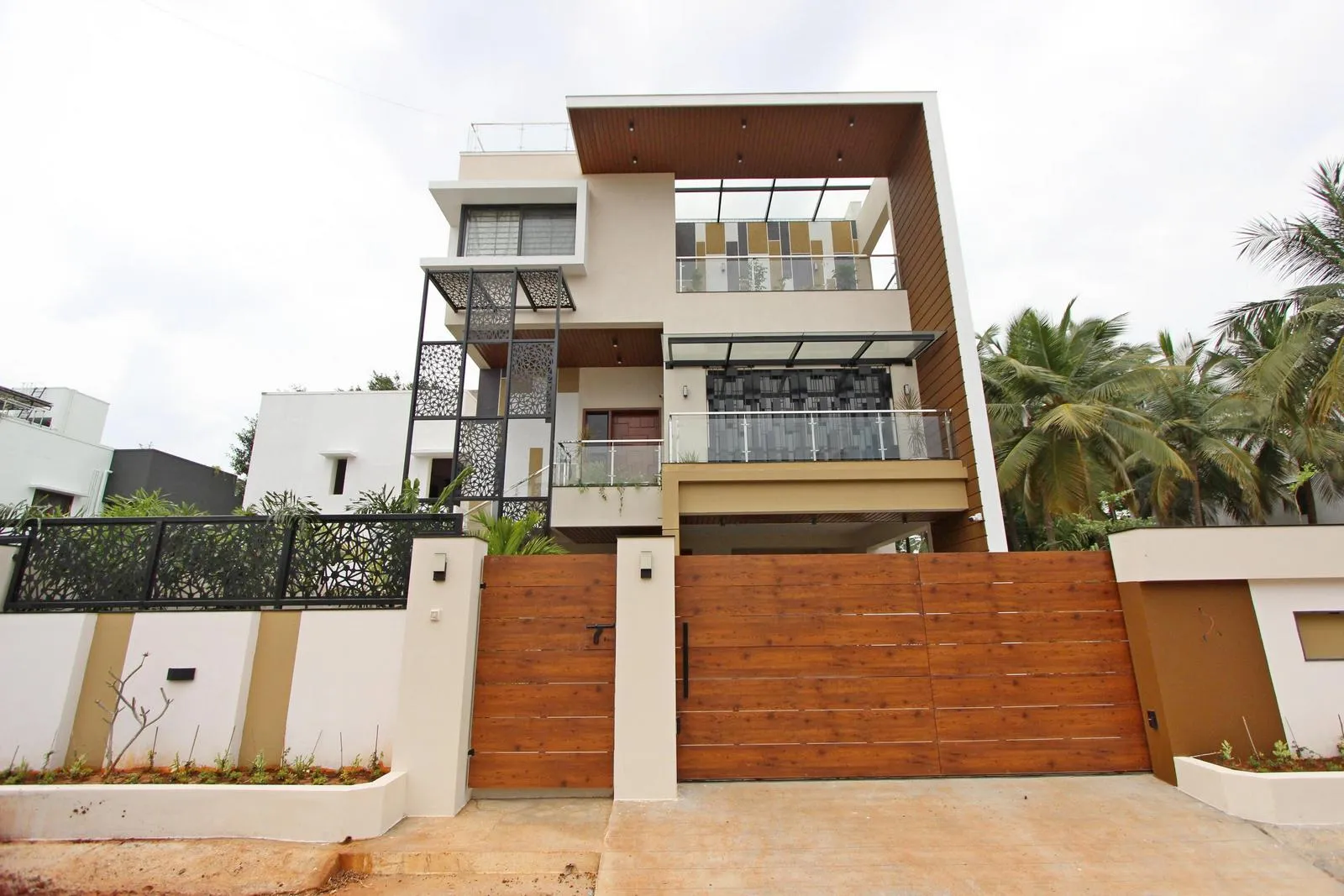 The house exterior features clean, interlocking forms that add depth and visual rhythm. Cantilevered balconies, roof frames, and vertical screens provide shade, texture, and a strong connection between indoor and outdoor spaces.