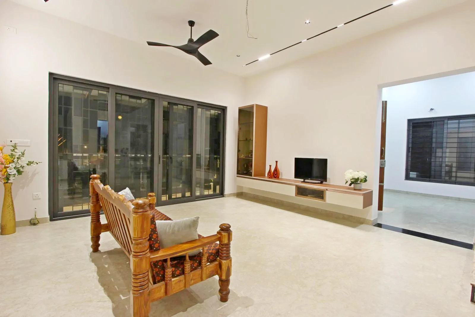 The first-floor living room is the social hub, with sliding glass doors to the balcony for light, ventilation, and views. The TV wall and nearby foyer provide clear focal points and smooth circulation.