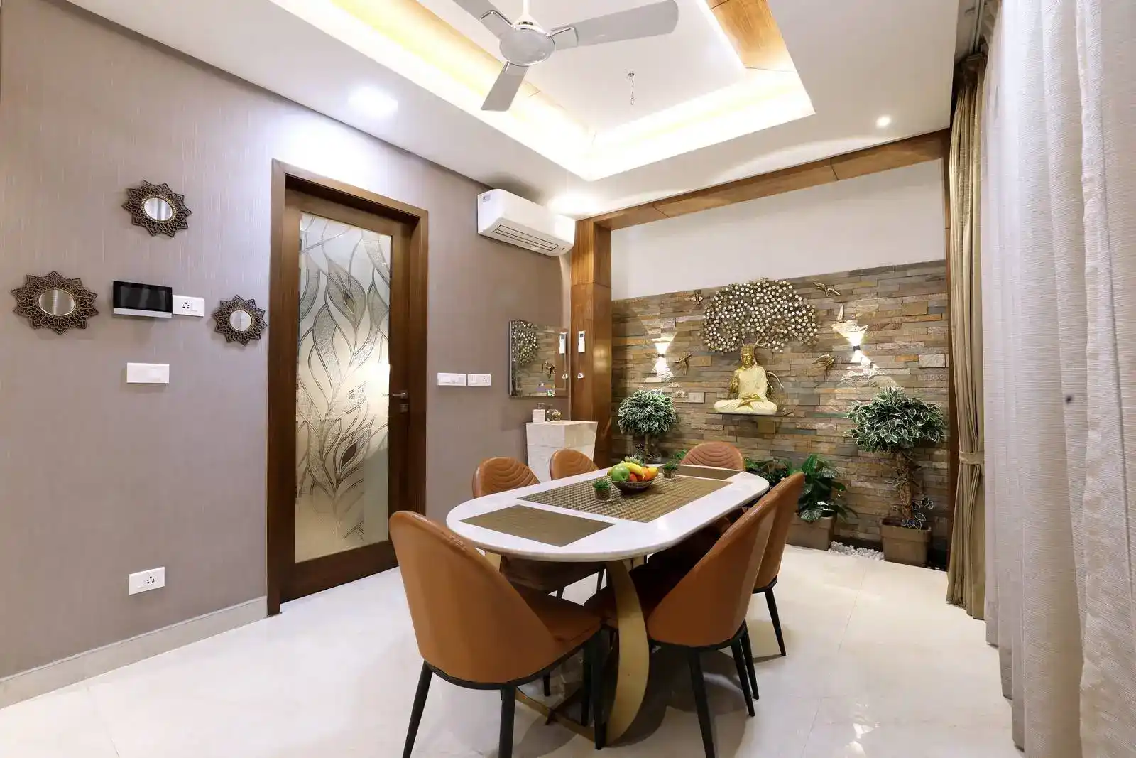 Centrally placed, the dining area gains a tranquil focal point with a Buddha statue and potted plants, while a feature wall with an indoor courtyard enhances light and depth.