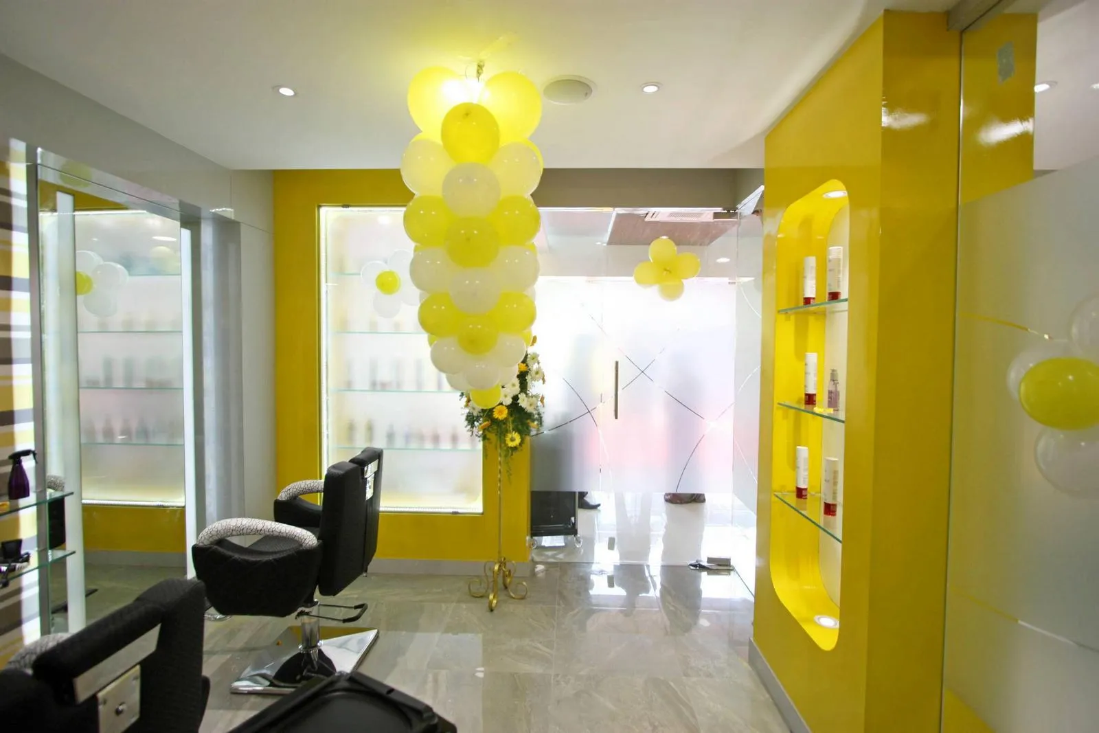 The entrance and interior combine bold colors, sleek materials, and reflective surfaces to create a vibrant, welcoming salon environment. Strategic lighting, polished flooring, and integrated display niches enhance spatial depth, functionality, and visual appeal.
