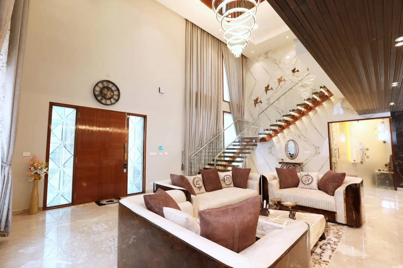 Seamless flow from entrance to living area with glass panels enhancing light. Personalized with wall art and decor, and tall curtains highlighting vertical space.