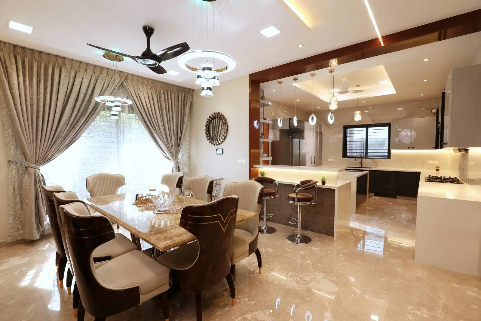 The open-plan space connects the dining area to the kitchen through a wide wooden-framed opening. A breakfast bar with stools partially separates the kitchen, offering a functional and visual transition between zones.