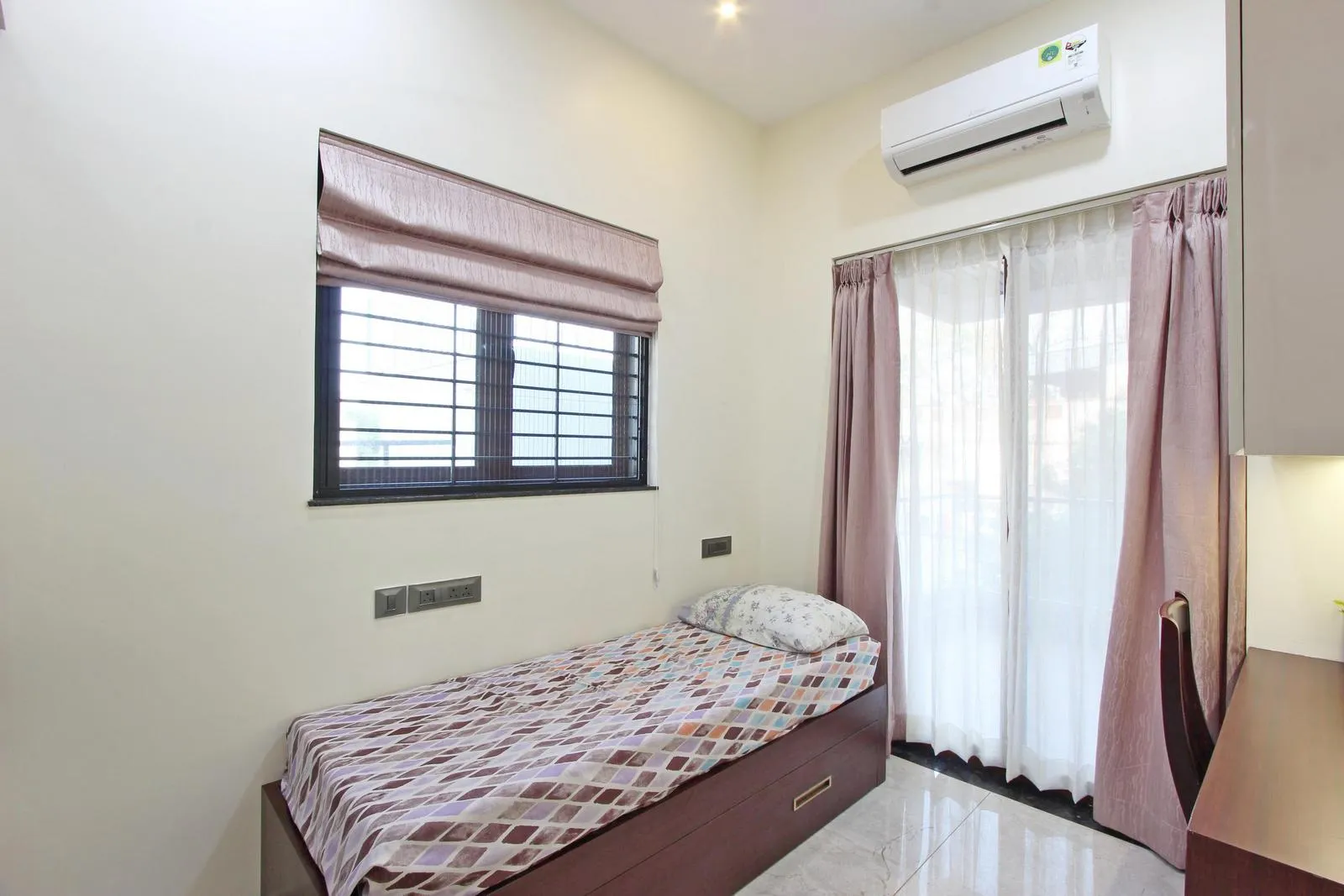 This single-occupancy study room is efficiently planned with a wall-aligned desk and integrated wardrobe to maximize usable space. Soft off-white walls, warm walnut wood furniture, and generous natural light create a calm, functional, and welcoming environment.
