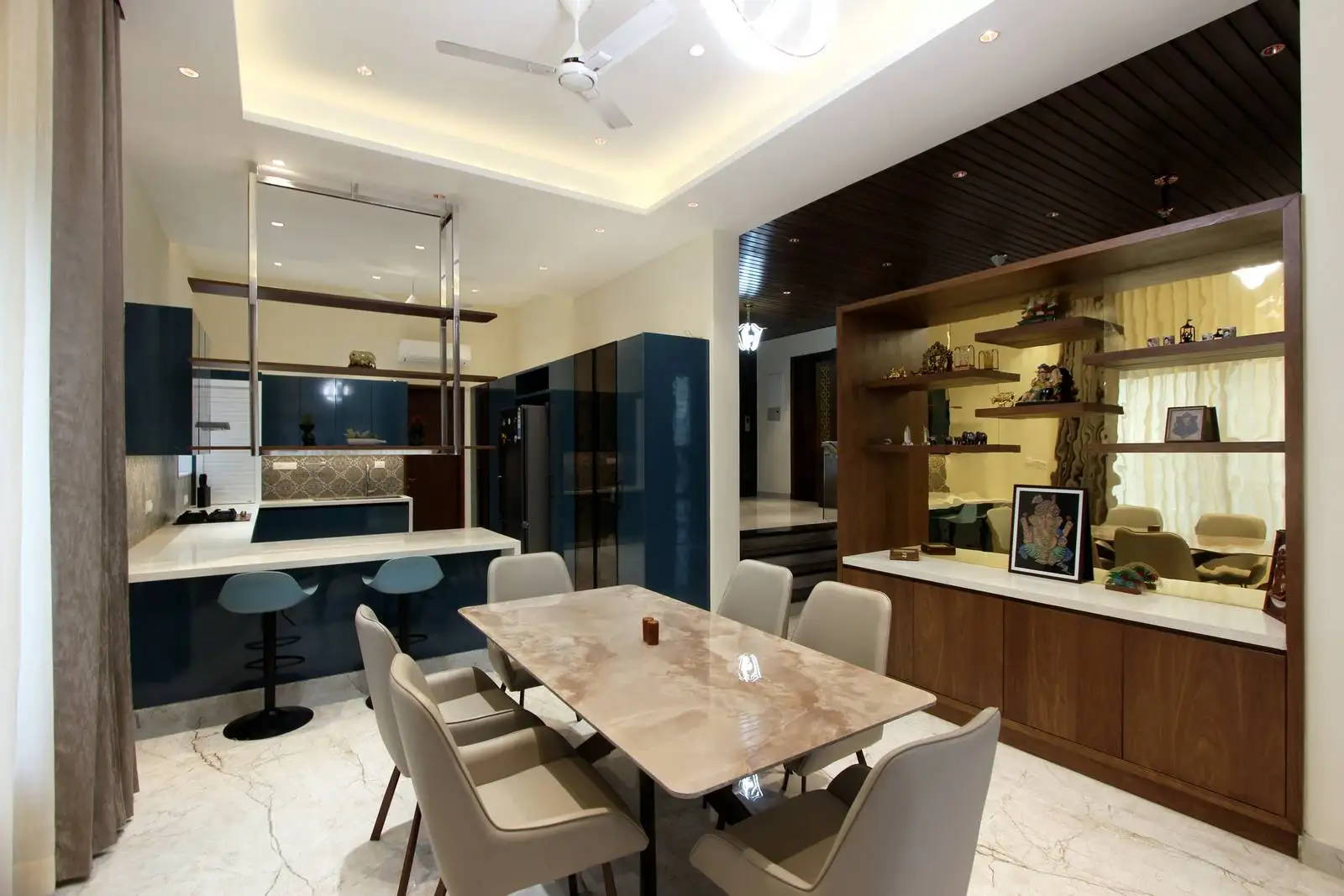 A sleek kitchen with glossy blue cabinetry, light countertops, and a breakfast counter that seamlessly connects to the dining zone.