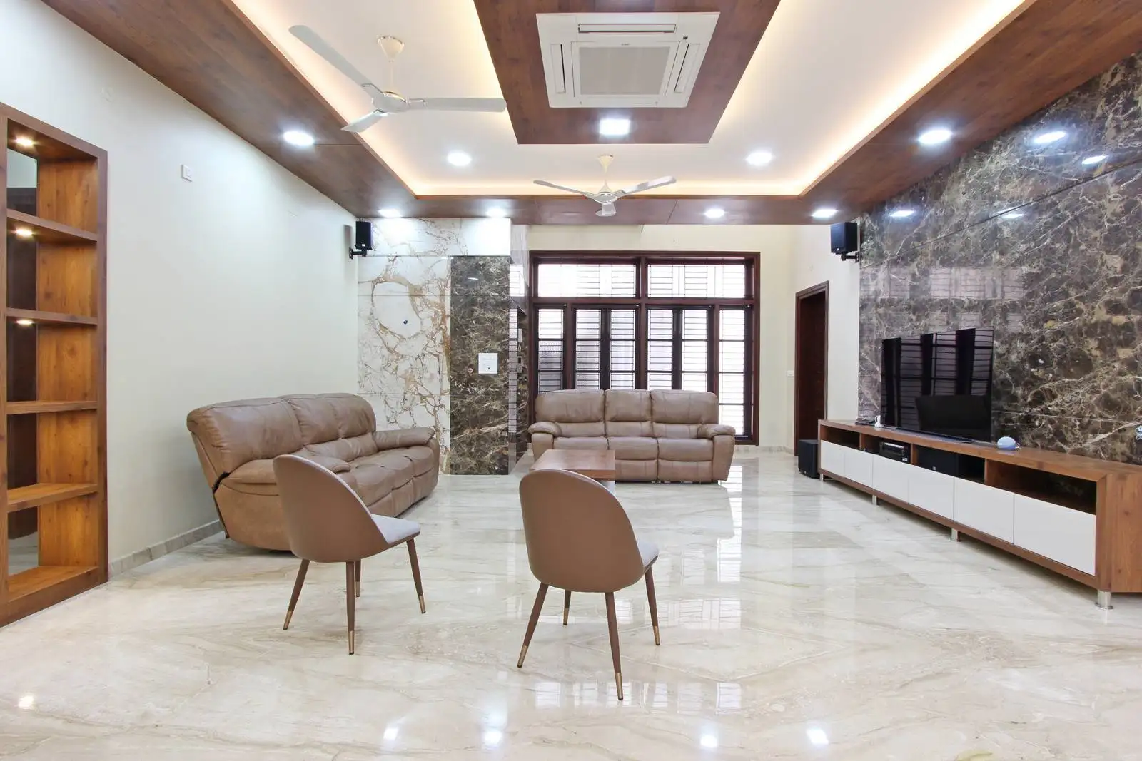 Spacious living room with warm-toned seating, marble flooring, and a striking dark accent wall, designed for comfort and modern elegance.