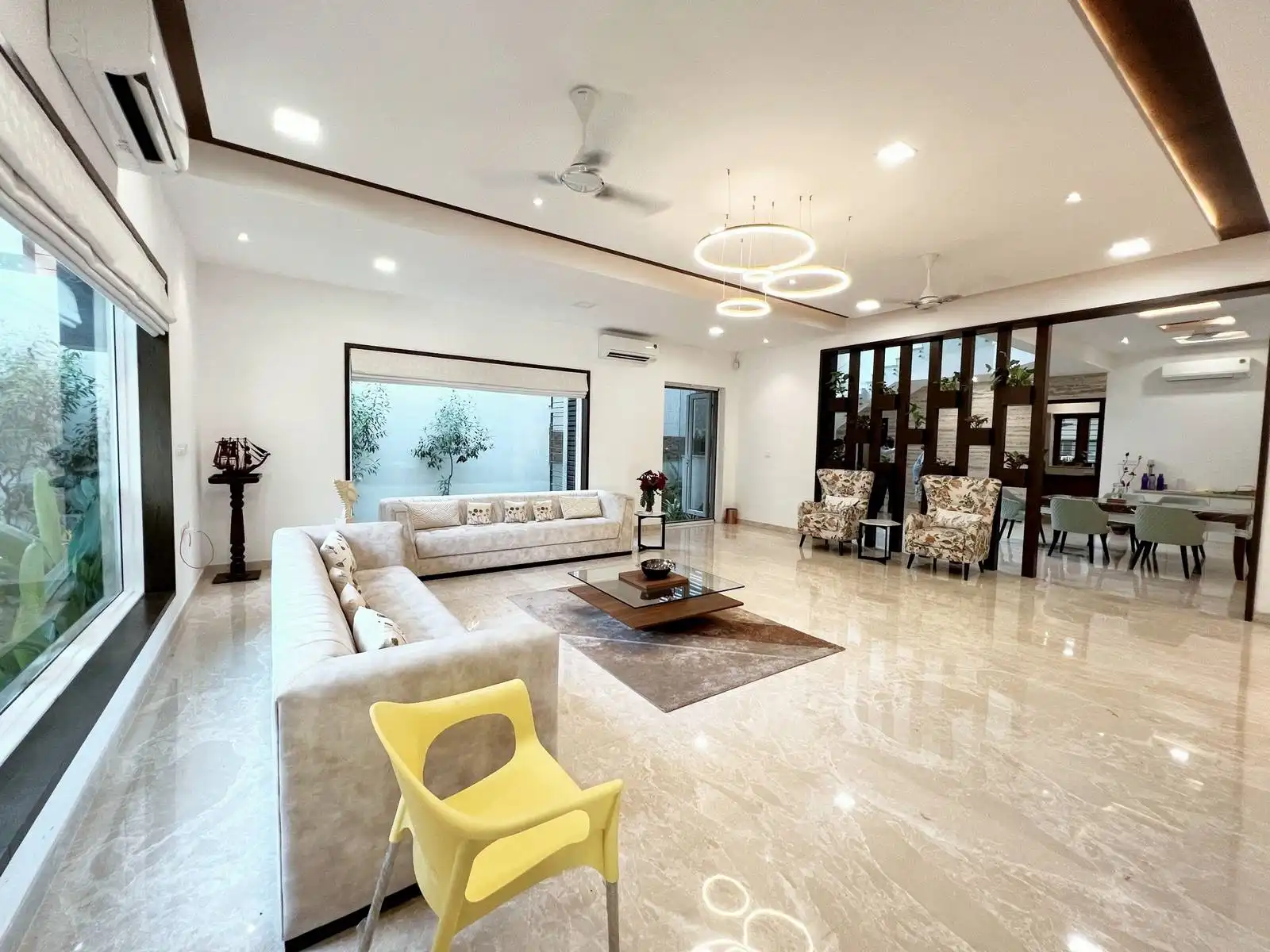 The flooring is polished marble with subtle veining, contributing to a luxurious and reflective surface. Walls are painted in crisp white, enhancing brightness and providing a clean backdrop for furnishings.