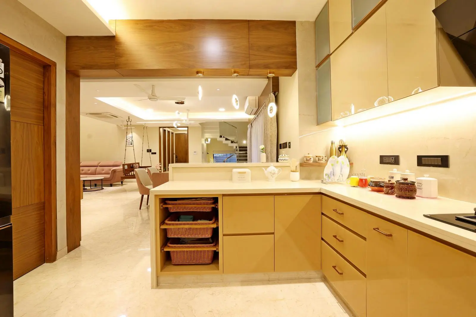 White quartz countertops and beige marble floors create a sleek, continuous look, while wooden ceiling bands and door frames add warmth and texture to the modern design.