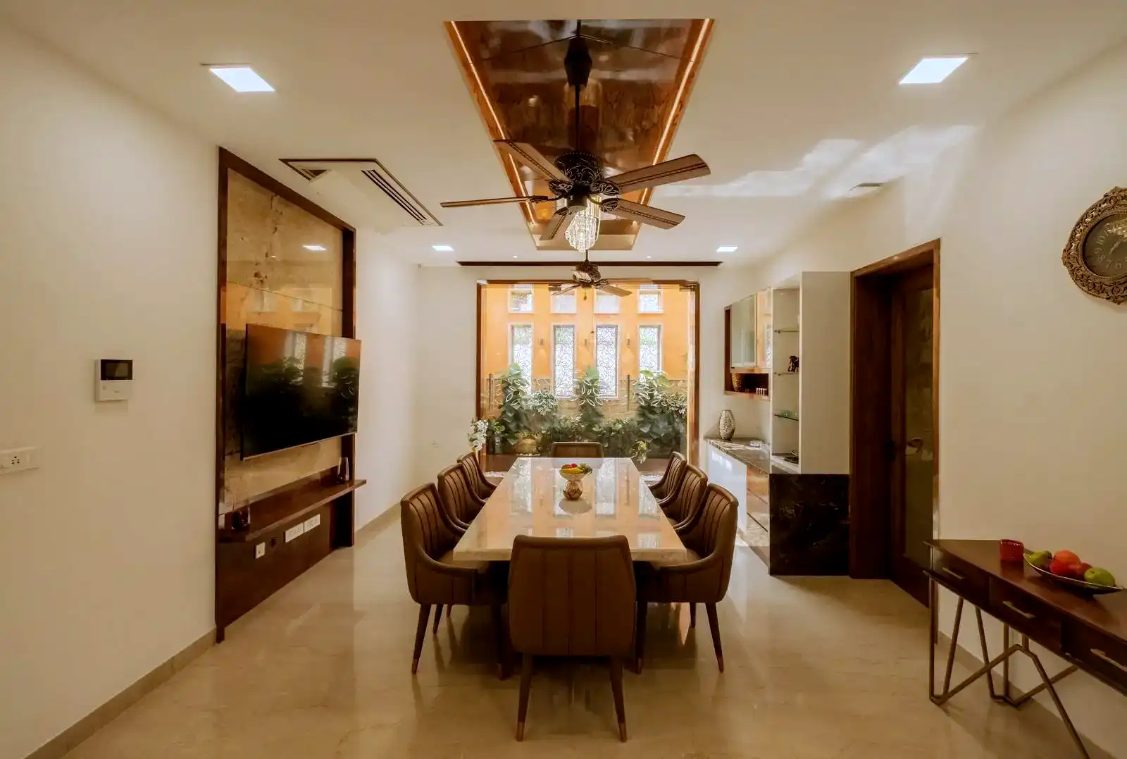 The space is visually extended by the large window at the back, which opens up to a lush courtyard, creating a seamless indoor-outdoor connection.