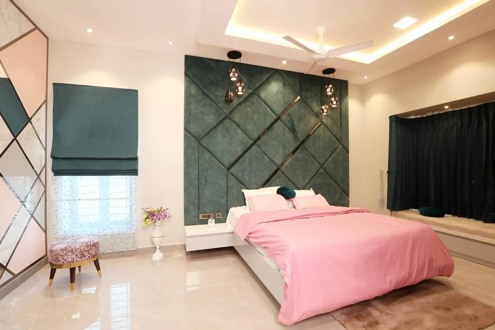 Plush teal geometric paneling creates a bold feature wall behind the bed, complemented by pendant lights and minimal, serene decor.