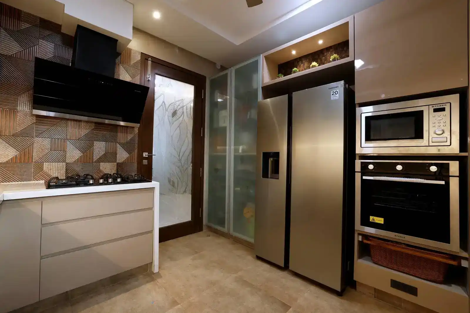 Kitchen features a linear, highly functional layout with easy access to all work zones. A geometric earthy-toned backsplash adds texture and visual interest, enhancing the space’s design character.