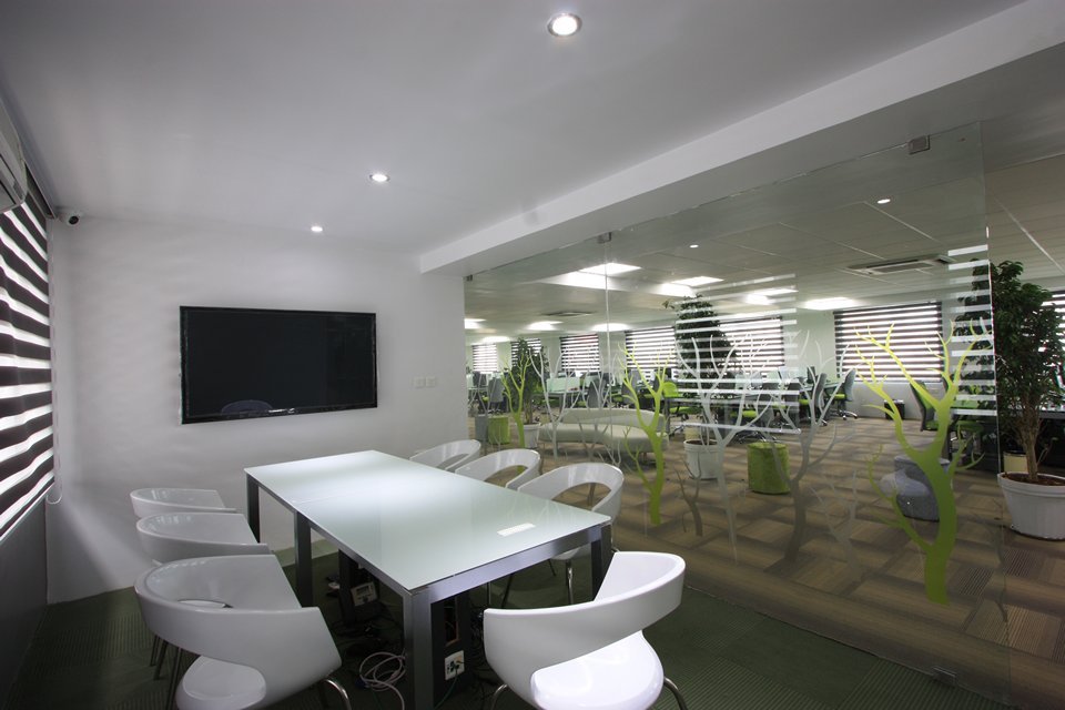 Meeting room with glass table, curved white chairs, and a patterned glass wall that offers visual separation and a refined, collaborative atmosphere.