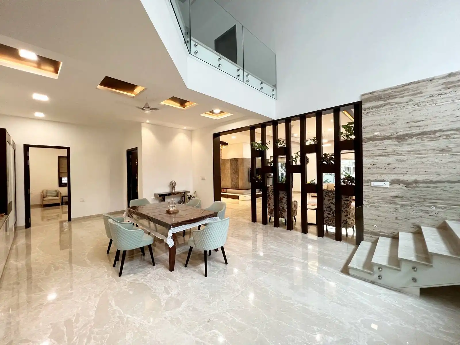 The dining area is centrally located in an open-plan layout, seamlessly connecting to adjacent spaces such as the kitchen and living area. The space benefits from a double-height ceiling, which creates a sense of openness and grandeur.