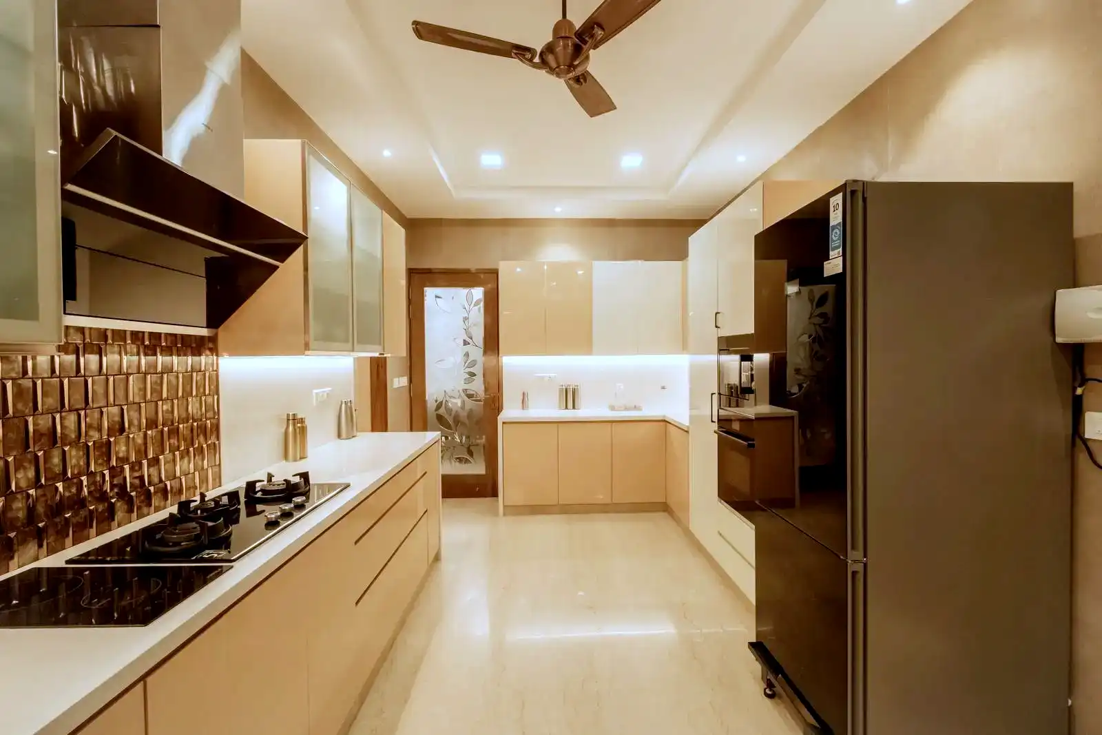Two-tone cabinetry combines high-gloss, light-toned cabinets with warm beige finishes, creating visual interest and defining distinct zones while maintaining a cohesive, modern aesthetic.