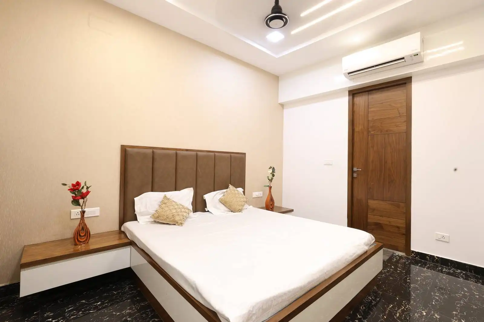 Bedroom features a minimalist layout with a centrally placed bed and integrated side tables. The headboard is upholstered in a soft, neutral fabric, adding comfort and a touch of luxury.