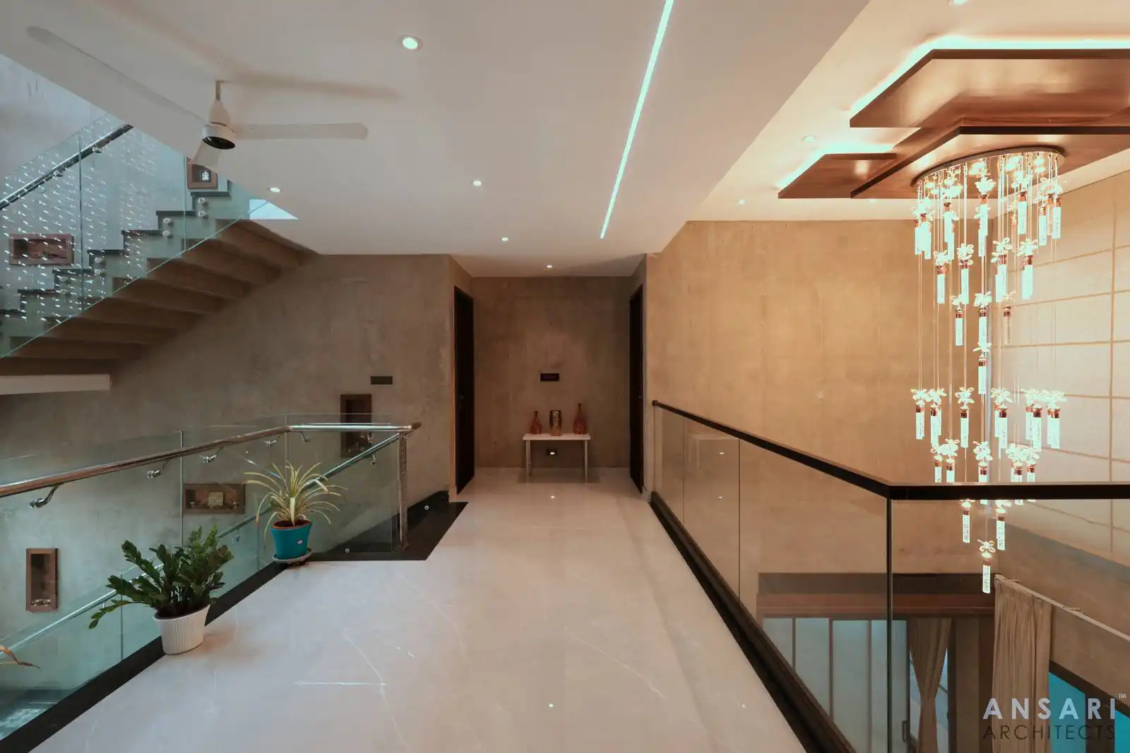 Upper-level family area with glass railings and sculptural stairs overlooks a double-height courtyard, blending openness with refined, contemporary design.