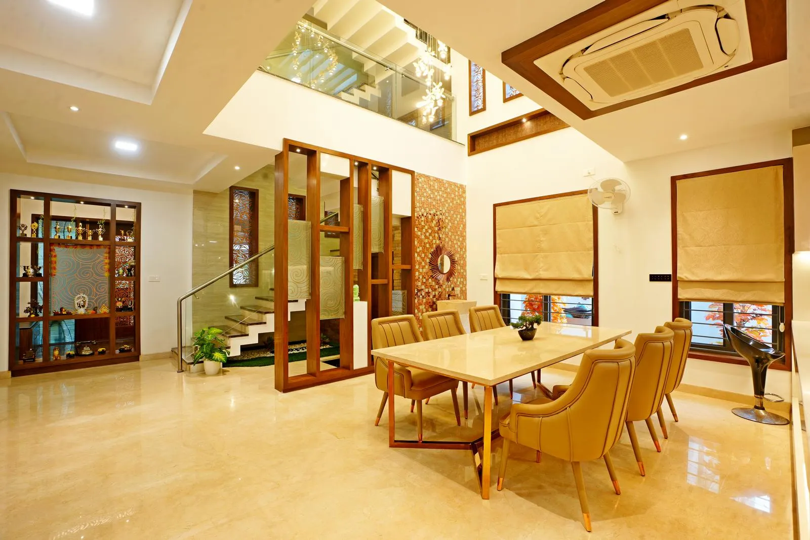 The dining area ( 19'0" x 22'0" sq. ft ) is centrally placed with a double-height ceiling, a glass-and-wood staircase, and an indoor courtyard beneath, creating openness and visual connectivity. The common toilet is discreetly located to the right of the staircase, maintaining privacy while ensuring accessibility.