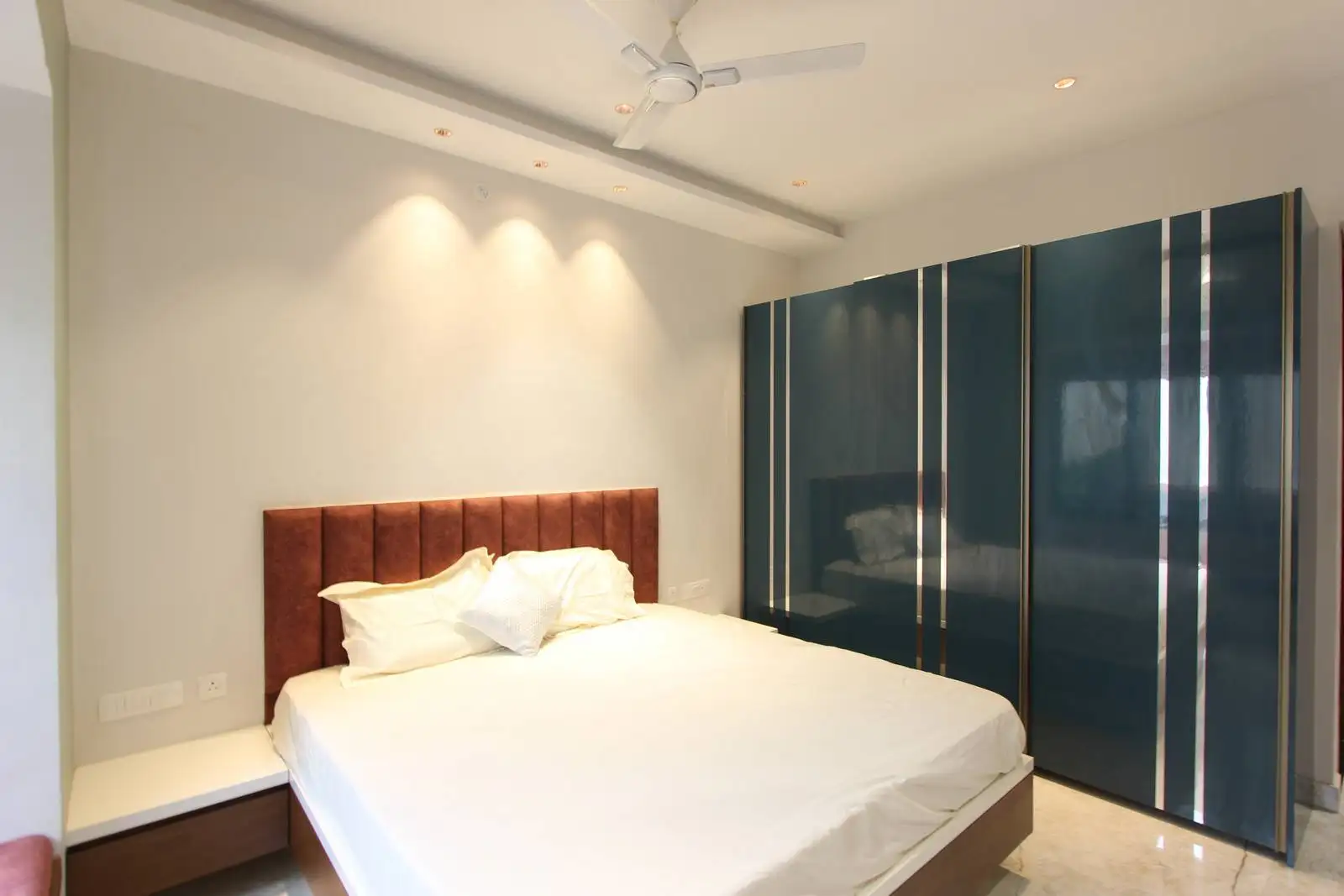 The large bed and bold wardrobe create two strong focal points, balanced by the neutral backdrop.
