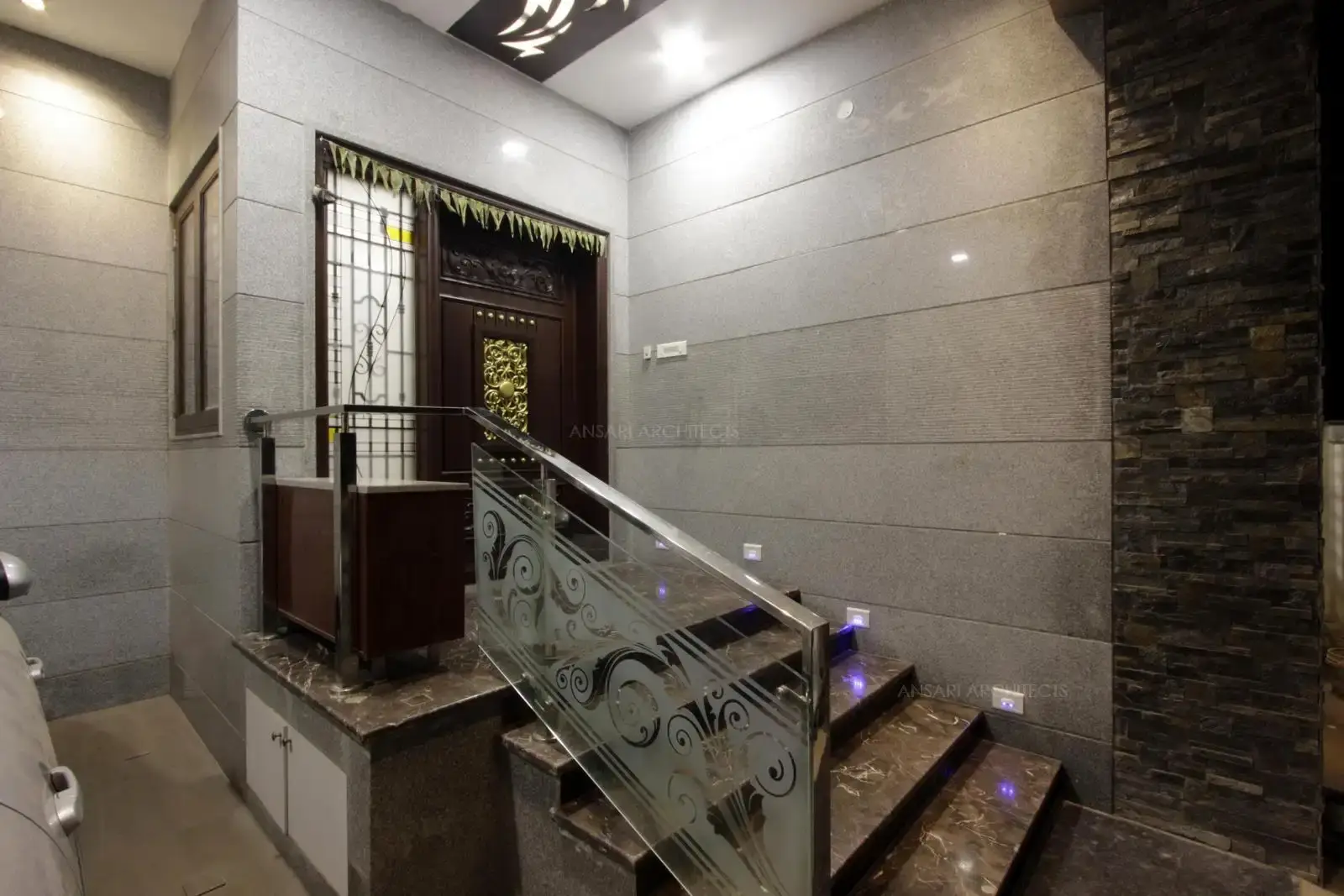 The entry area is further detailed with marble and stone textures on wall, glass handrails integrate well with solid finish doors and glass panels giving a light look.