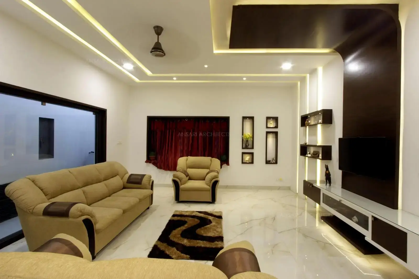 Wood wall panelling extends from wall to ceiling and backlit with strip lights that provide a soft glow, which works as a focal point, niches with inset wood texture acts as a decor element with the same language that are interestingly composed with lights.