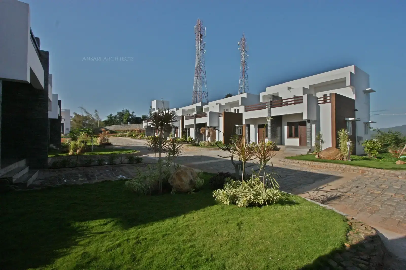 Stone-paved driveway and defined pathways offer smooth access, guest parking, and a clean, organized landscape layout.