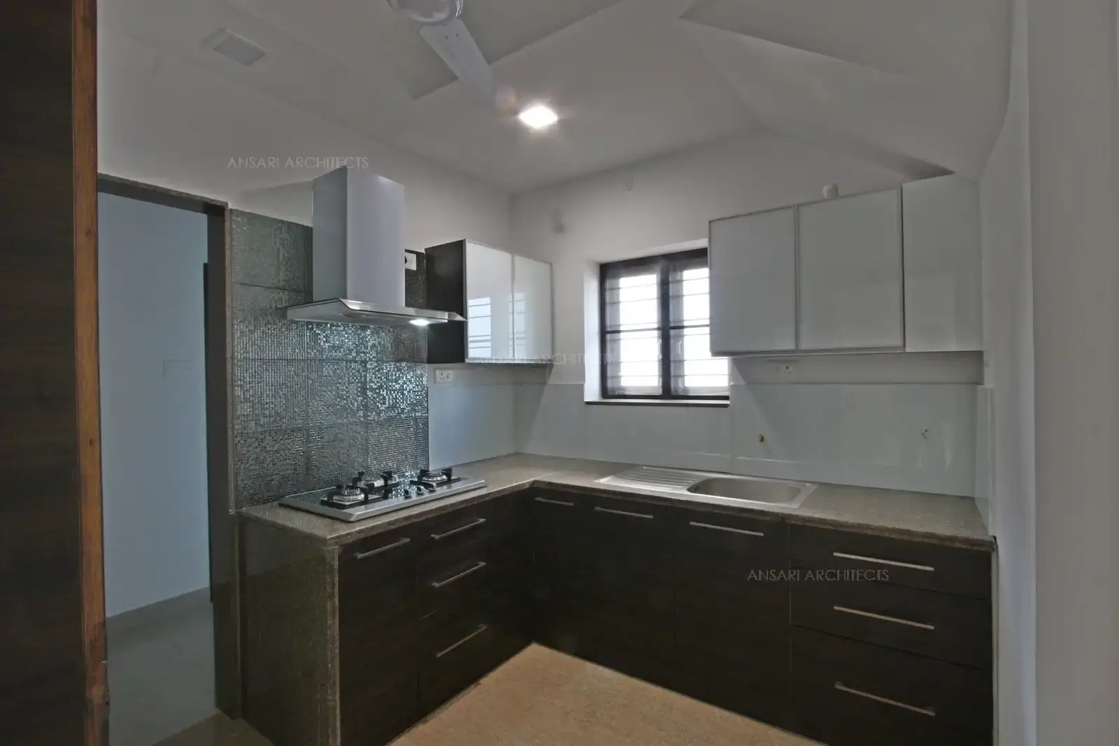 L-shaped kitchen with dark wood lower cabinets and glossy white uppers for contrast and efficiency.Maximized corner space and countertop area enhance functionality and visual appeal.