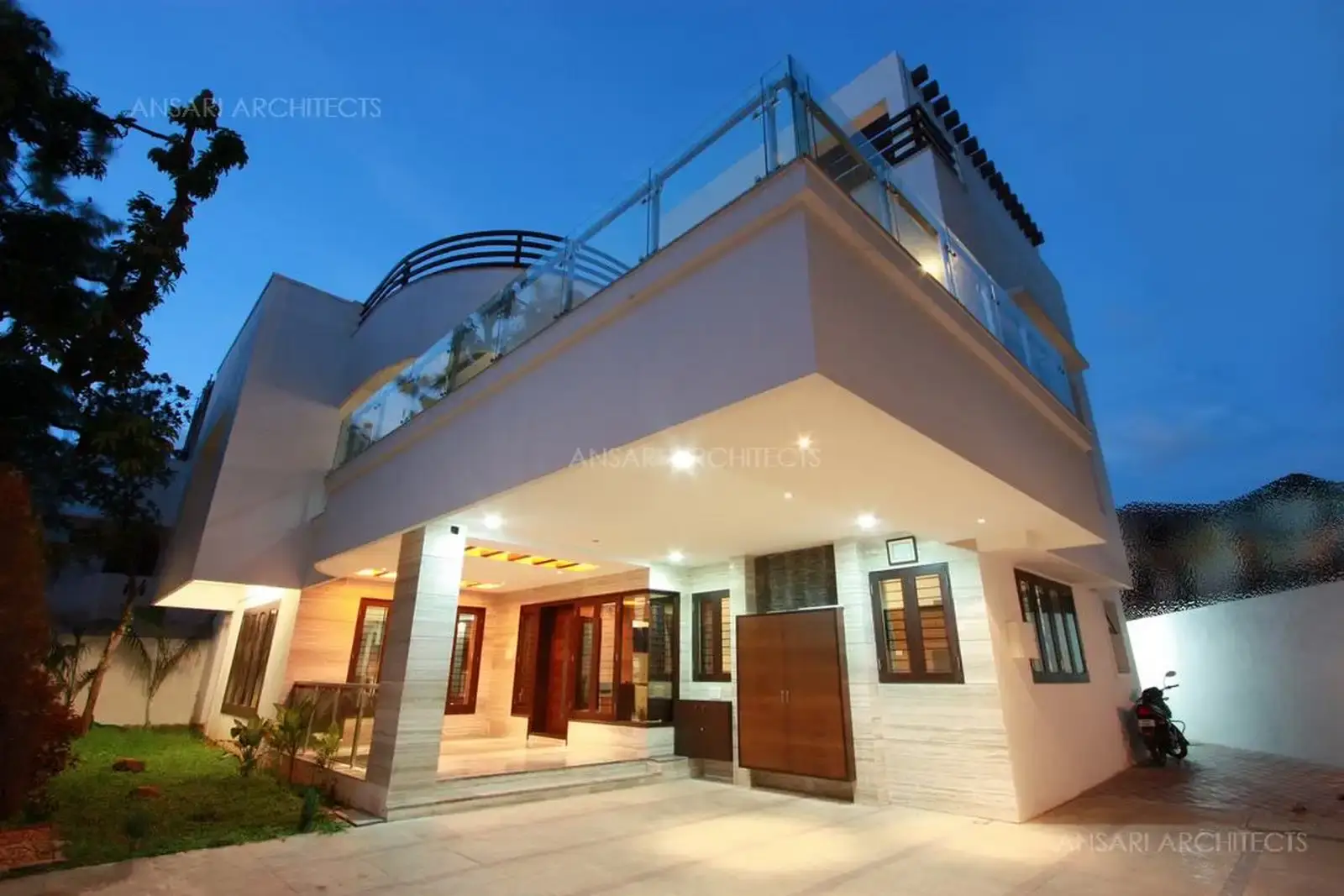 Exterior view of the house has been designed in simple white finish with glass and wooden handrails at different levels for a contemporary look.