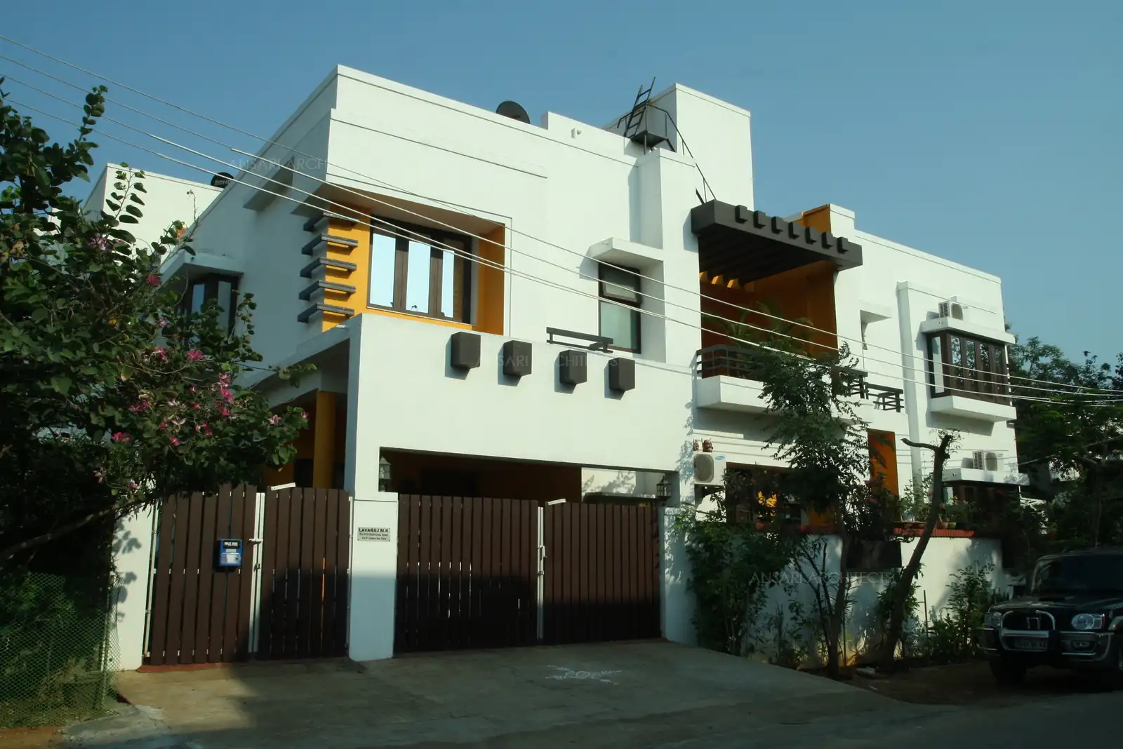 Exterior view of the house has been designed in simple white and finish in the pergolas and the main gate for a contemporary look.