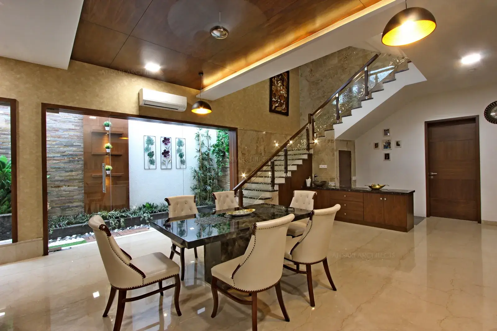 Leather upholstered chairs are classic and elegant table with wallapaper. Metallic pendant lights add a modern touch while the wooden unit multitasks as a pantry unit and a storage cabinet. A wholly neutal colour scheme is considerably livened up with the touch of walllpaper for the entire wall with dark cladded ceiling as veneer panels.
