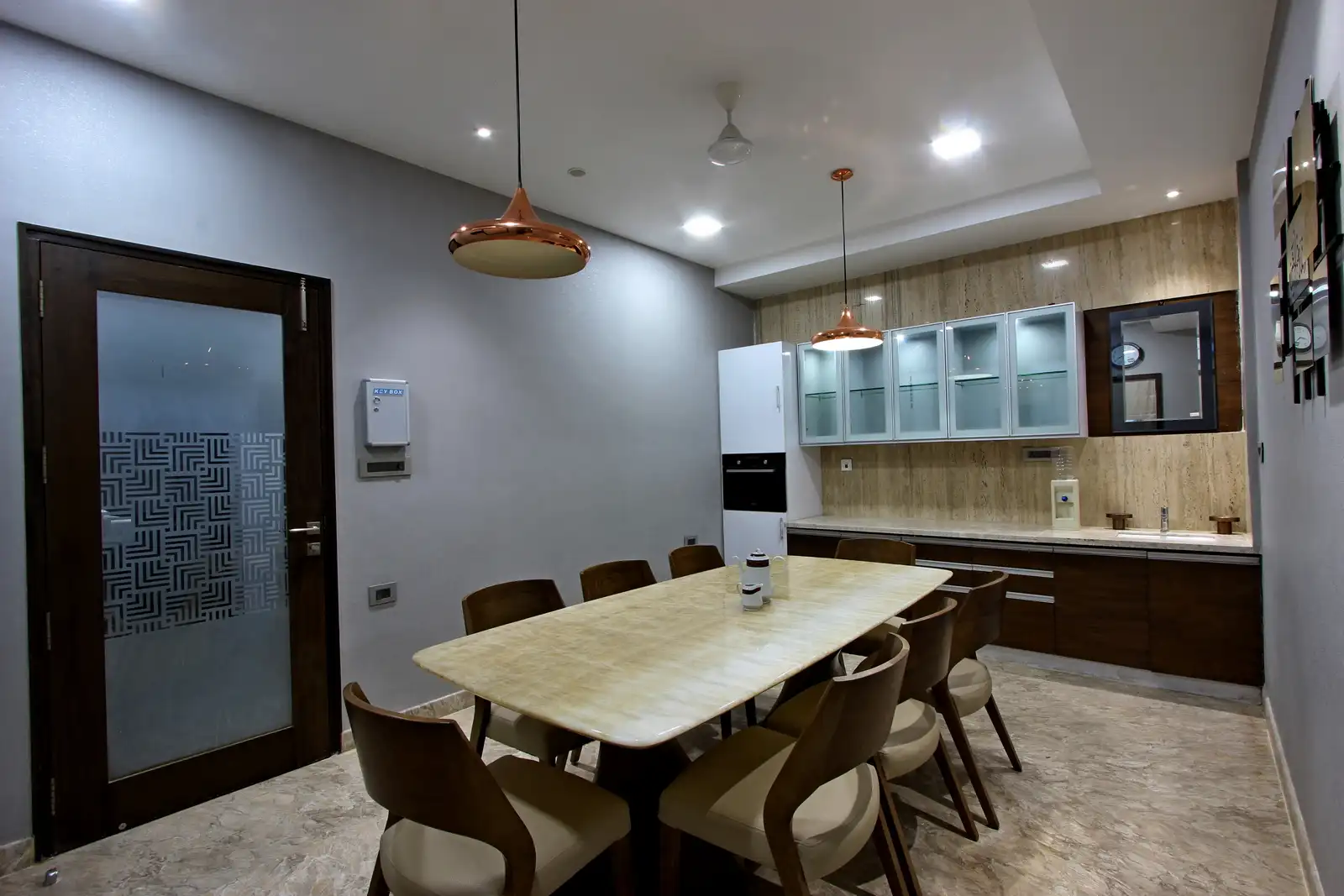 The panelled wall defines the dining area others for white contrast , the natural wood of the dining table inject an organic feel play of all elements Space is complemented by storage and pantry are that adds punch of veneer and a hint of a feminine touch