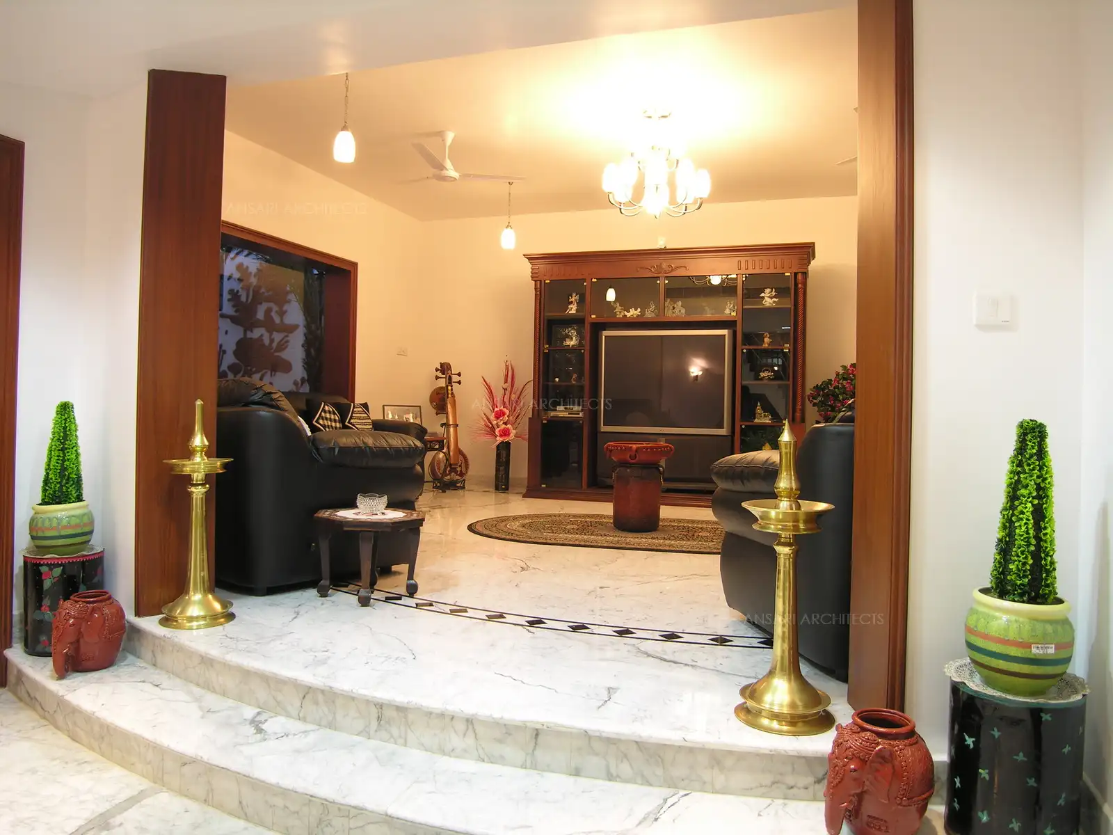 The entrance to the living room is framed by wooden panelling, and the flooring is white. Italian Statuario Marble.
