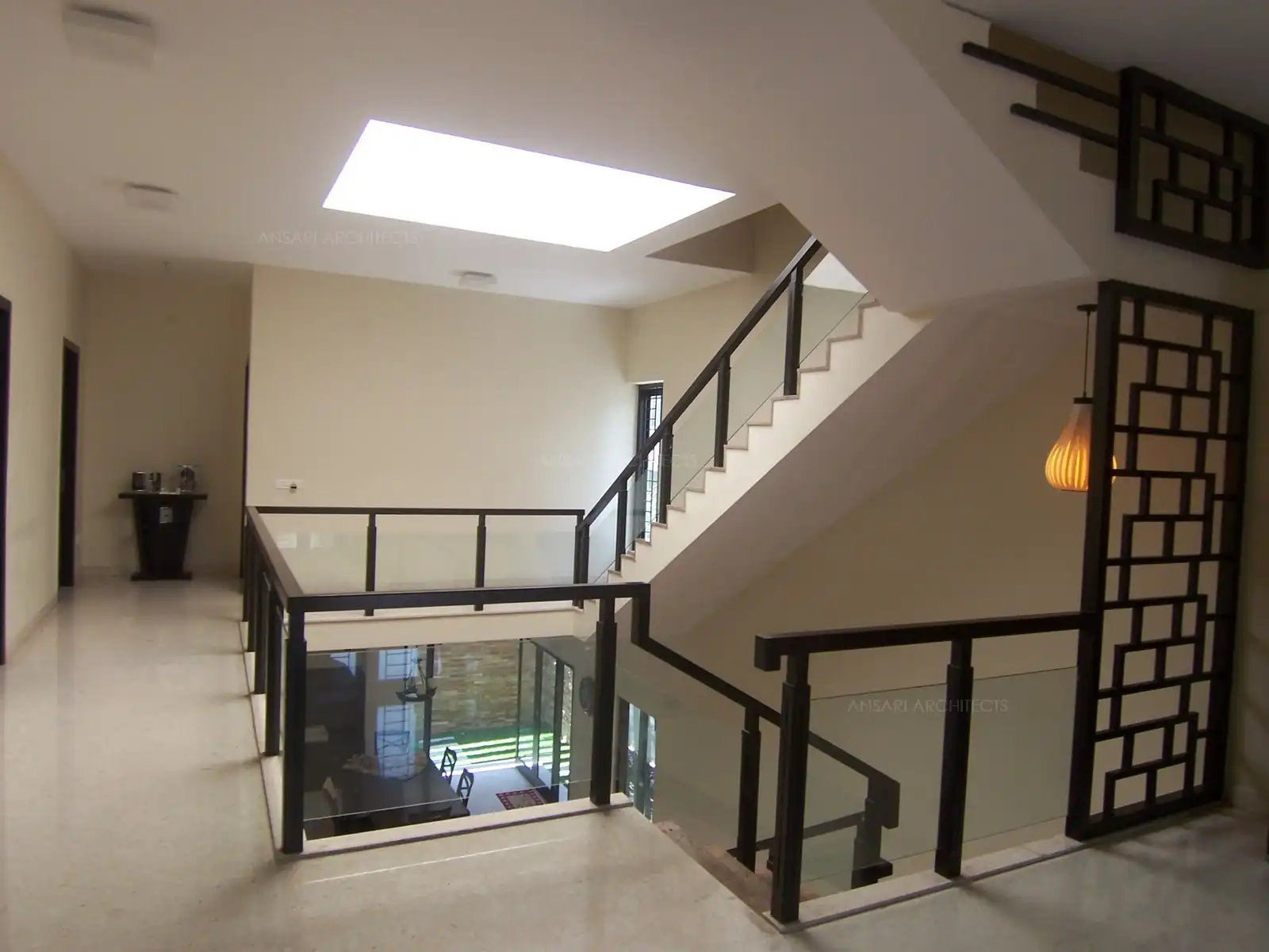 Staircase railing in wood and glass designed around central courtyard.
