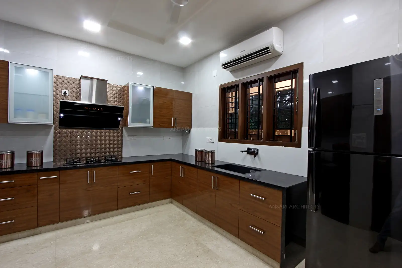Granite countertop and cabinets in laminate finish create a bright atmosphere along with amrble flooring and honey-toned square tiles backsplash gives the kitchen a transitional style. A soft colour scheme and dark tones create a luxurious style.