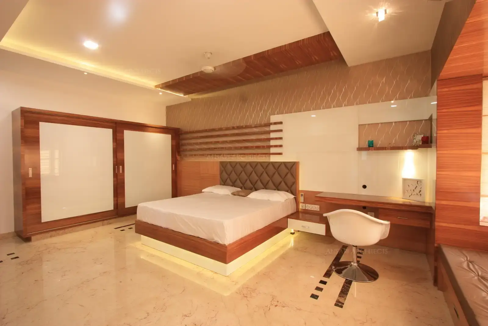 Different textures are created in the finishes with the use of glass,wood and wall paper in this master bedroom.
