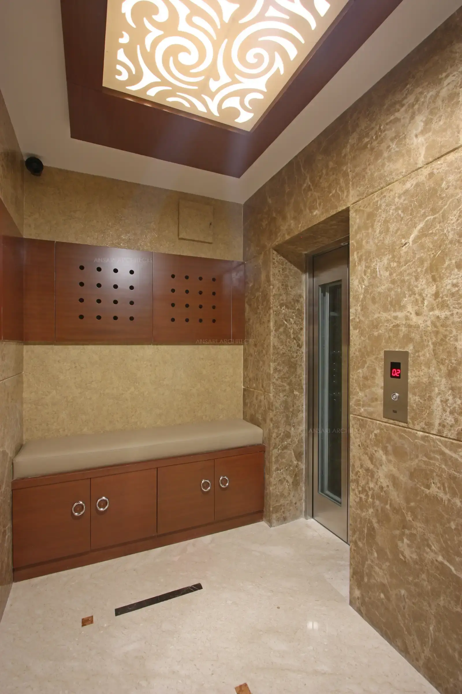 The furniture element defines the space, cushioned seaters and wooden textures also functional with storage cabinets and punctures in wall panels, decorative panels with abstract patterns provide ethnic accents.