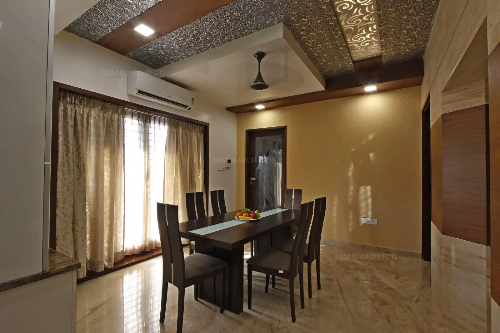 Long wooden table and the clean marble flooring helps balance the rustic feel of the room. For a splash of unhindered opulence the dining room offers a multitude of design elements which elaborate the space. Marble clad walls offer serenity to the space along with the wallpaper as soft tones of the room. Curtains transform the room's decor.