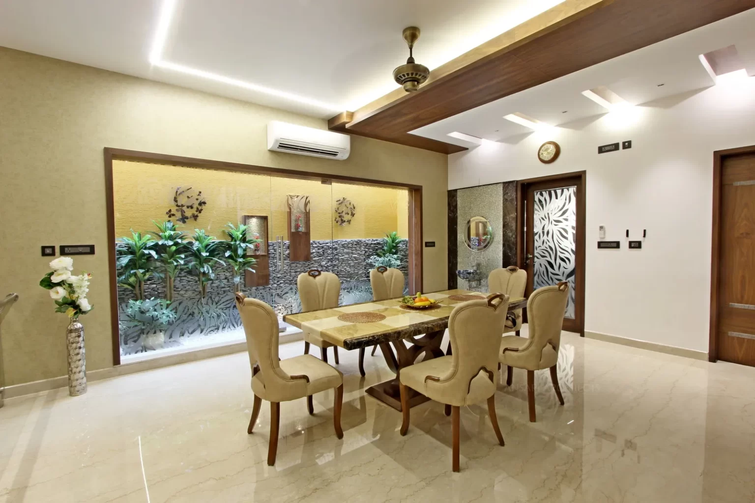The wallpaper highlights the entire courtyard wall and thereby the visual flow of the dining area is increased by achieving a connectivity with the courtyard along with the wood cladding feature.