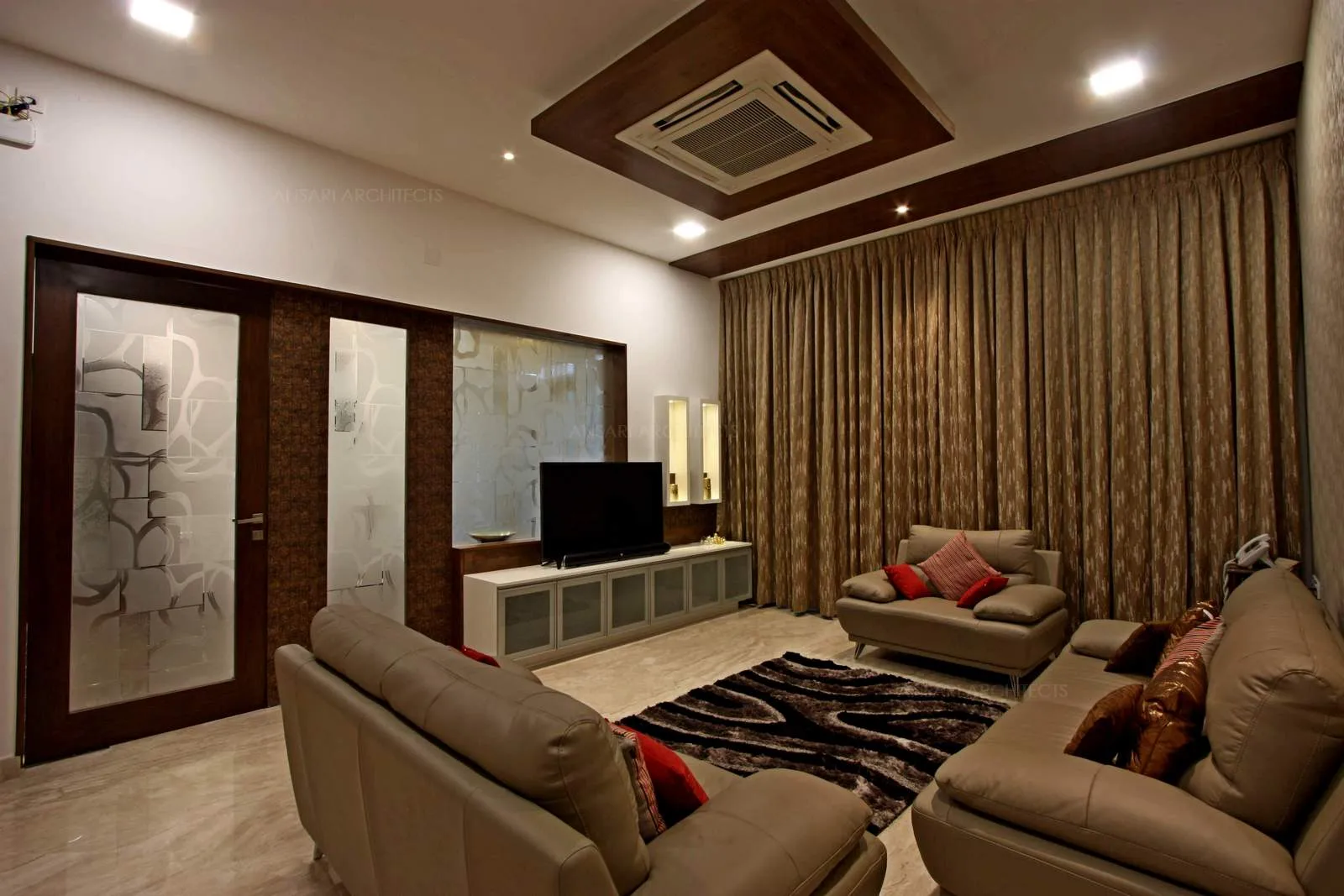 The living room is neutral, the only colour element acknowledging the furniture scheme, the soft cushions in beige tones with pe4rfect layering of colours of the decor scheme in brown tones, the lavish tie-back drapes in curtains.