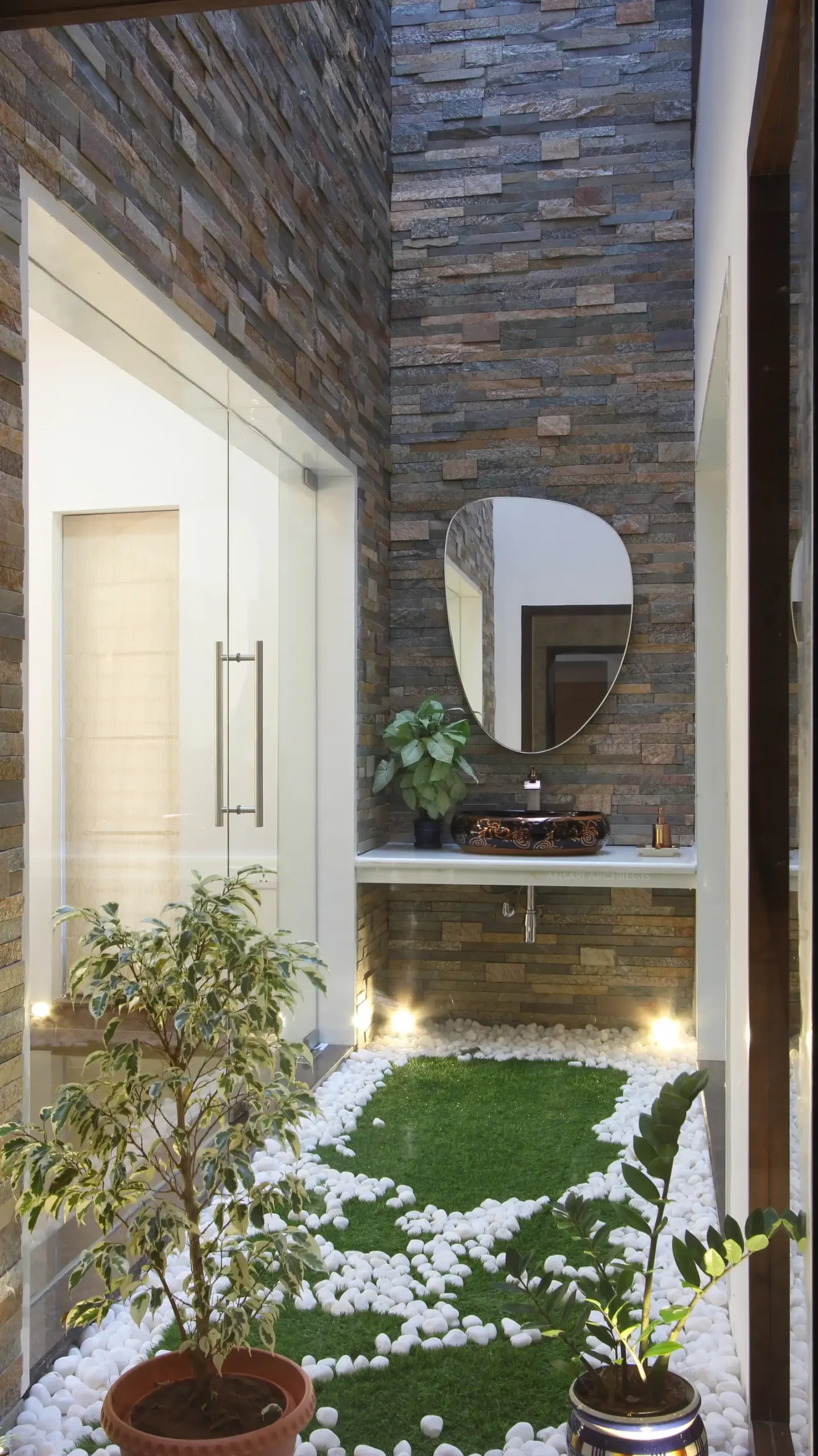The courtyard welcomes natural light, with stone- clad and a small vanity unit with mirror is situated as the focal point, also with hardscapes complementing the entire space.