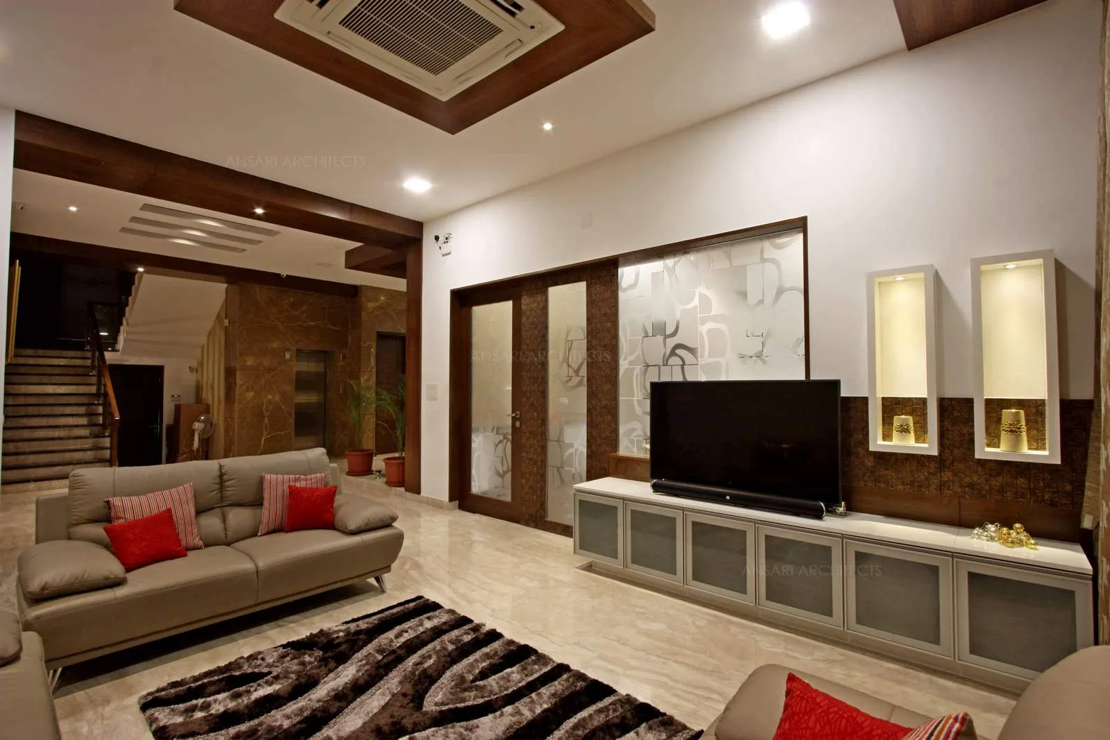 Dark wood ceiling demarcates the entire area, interplaying of varying textures, between deep tufted sofas and plush carpet makes for a sumptuous living room setting amply proving that beige scheme.