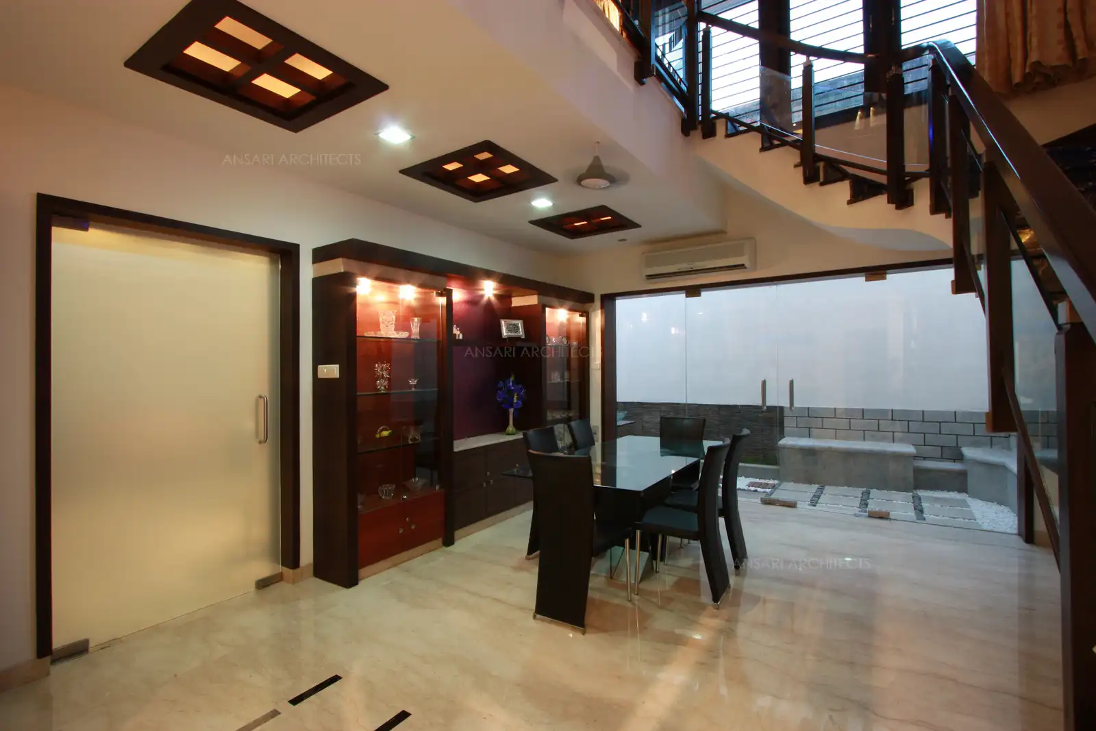 False ceiling designed in the dining room highlights the crockery unit which has similar lines and shape with matching veneer.
